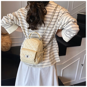 Close-up of a mini quilted backpack featuring a silver twist lock and chain strap detail