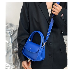 Close-up of a vibrant blue leather mini handbag with round handle and adjustable strap