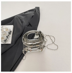 Dettaglio borsa da sera argento metallizzato con catena a sfere e design ad arco