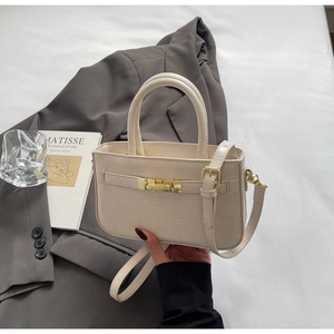 Detail of cream faux crocodile texture tote bag with gold hardware on grey blazer