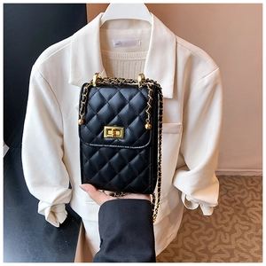Close-up of black quilted crossbody bag with gold chain strap and metal turn-lock closure