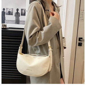 Chic cream half-moon bag in pebbled leather styled on model with gold zipper detail