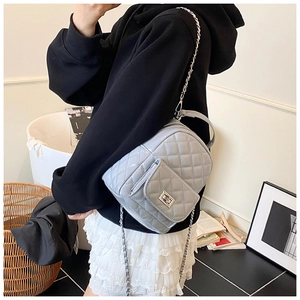 Quilted mini backpack with silver chain strap shown in a cozy home setting decor