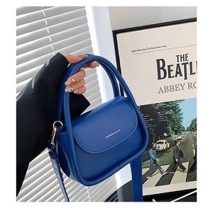 Close-up of a blue leather handbag with gold hardware and FASHION & BAGS logo detail