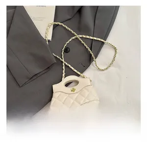 Detail of white quilted mini bag with golden flower clasp and chain strap on grey blazer