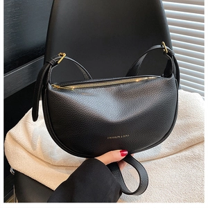 Detail of black crescent leather bag with lychee texture and gold metal zipper