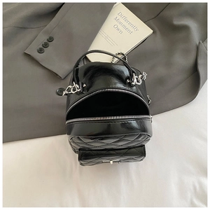 Detail view of mini black quilted backpack with silver chains and metallic zipper textures