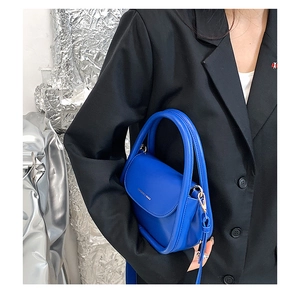 Blue leather crossbody bag showing actual size and scale on a model with silver background