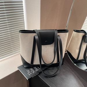 Sac cabas rétro en toile avec détails en cuir noir sur une table en bois foncée