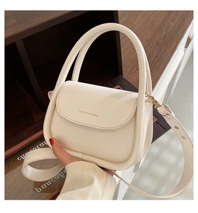 Close-up of cream PU leather handbag featuring gold Fashion & Bags lettering and handle