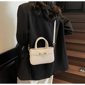 Detailed cream crocodile pattern leather bag with gold buckle on a classic suit