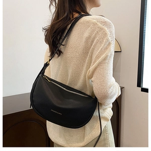 Close-up of black crescent crossbody bag with lychee grain leather and gold buckle details