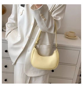 Detail of pale yellow crescent moon shoulder bag in matte PU leather with adjustable strap
