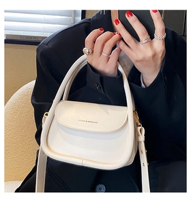 Detail of cream white leather mini handbag with top handle and gold tone hardware
