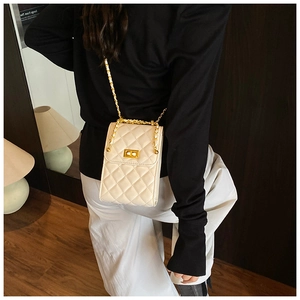 Rear view of a model wearing the cream quilted chain bag with gold metal hardware