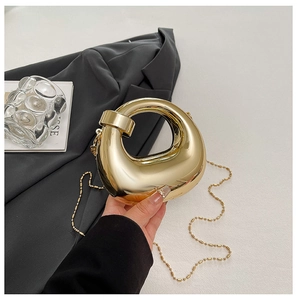 Dettaglio della borsa clutch geometrica in metallo con manico rotondo e catenina sottile