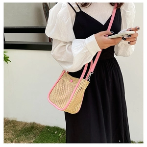 Detail of woven straw bucket bag with pink leather trim and matching snap closure