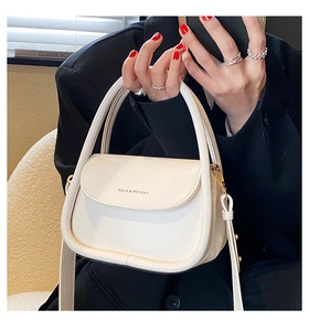 Detail view of white half-moon crossbody bag with gold hardware and fashion lettering