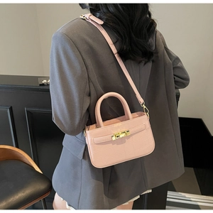 Pink stone pattern handbag with golden twist lock worn by a model in a grey suit