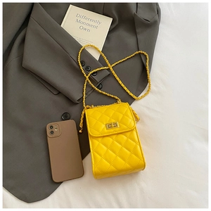 Macro shot of yellow quilted chain bag on a dark grey blazer with golden twist lock