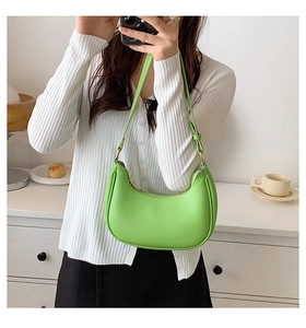Detailed close-up of a bright green crescent shoulder bag with smooth leather finish