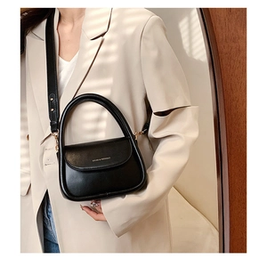 Detail of minimalist black leather handbag with gold lettering and detachable strap