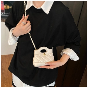 Close-up of white quilted mini bag with floral gold clasp and metal chain strap