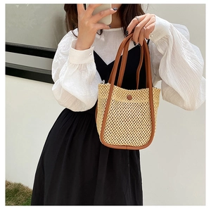 Detail of hand-woven straw cylinder bag with brown leather handles and vintage clasp