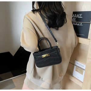 Detail of black faux crocodile skin handbag with golden rotary lock and crossbody strap