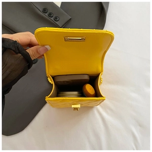 Interior storage of yellow quilted chain bag with phone, lipstick and powder compact