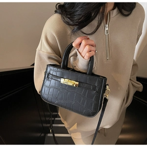 Detail of black crocodile texture leather handbag featuring a secure gold metal lock clasp