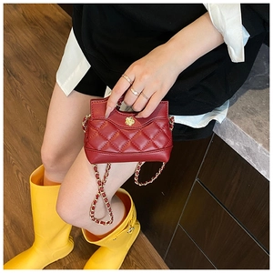 Detail of red quilted mini bag with gold flower buckle and chain strap on a model