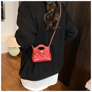 Detail of red quilted mini bag featuring a gold floral lock and chain strap on shoulder