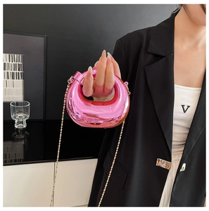 Dettaglio borsa da sera in acrilico rosa metallizzato con catena a sfera color oro