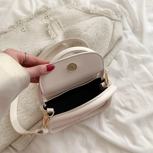 Close-up of cream crossbody bag interior with magnetic closure and golden hardware detail