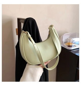 Detail of mint green crescent bag with smooth leather finish and gold hardware