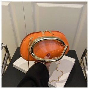Detail of orange high-gloss evening bag with large oval gold ring and thin chain strap