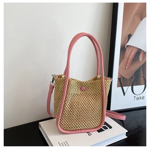 Detail showing the pink leather trim and intricate hand-woven texture of the straw bag