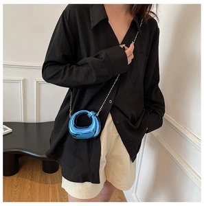 Dettaglio mini borsa blu elettrico metallizzato con catena dorata su camicia nera