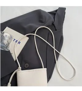 Detail of off-white lychee texture leather mini crossbody phone bag on grey blazer