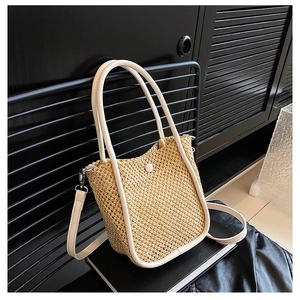 Detailed view of woven straw bucket bag with creamy leather trim and metallic rack base