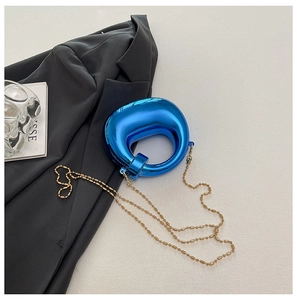 Pochette artistica in acrilico blu con nodo e catena dorata su abito nero