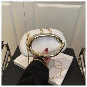 Detail of white evening clutch featuring an oval gold handle and delicate snake chain strap