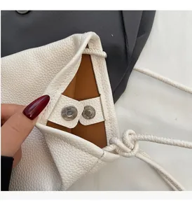 Detail of white lychee leather bag showing magnetic clasps and caramel interior lining