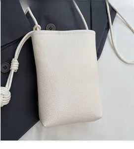 Detail of white lychee grain leather mini phone bag with knotted shoulder strap
