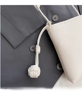 Close-up of beige lychee grain leather mini bucket bag with woven rope shoulder strap