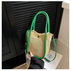 Close-up of beige woven straw tote bag with vibrant green leather handles and trim