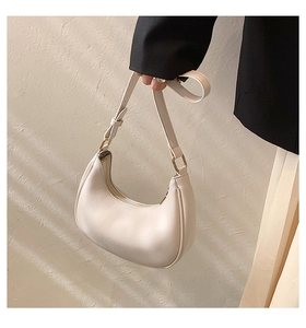 Detail of off-white leather hobo bag with gold metal buckle and adjustable shoulder strap
