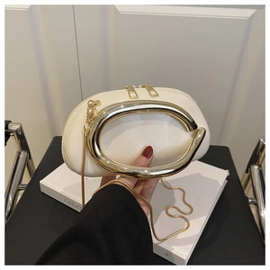 Detail of cream evening bag with gold ring handle and snake chain on decorative book