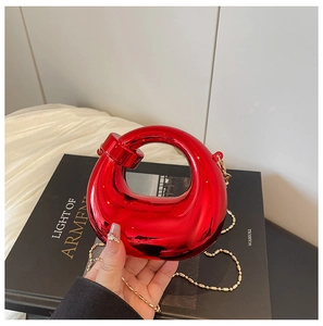 Dettaglio della pochette circolare in acrilico rosso lucido con tracolla dorata